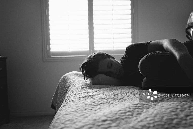 女人蜷缩在床上图片素材