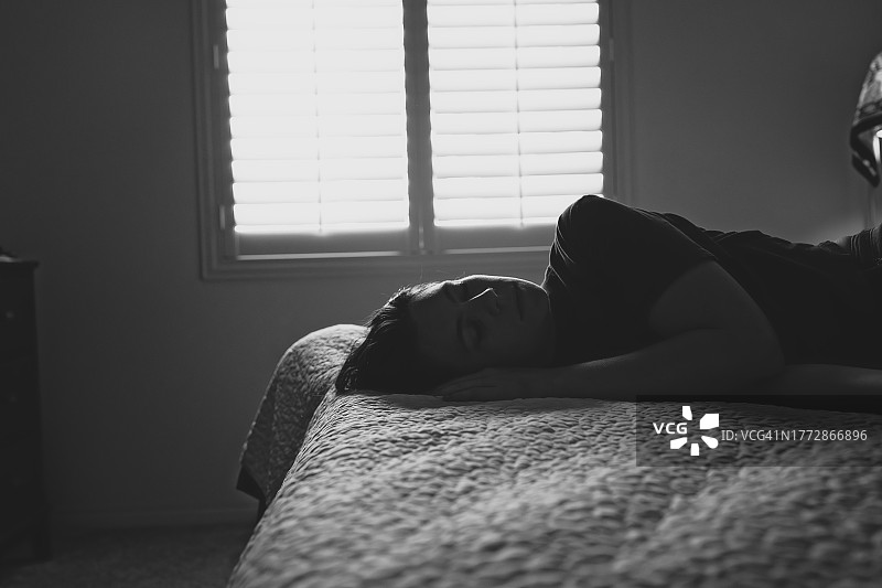 女人蜷缩在床上图片素材