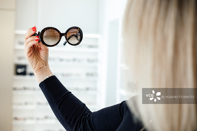 金发女子在店内手持时尚太阳镜图片素材