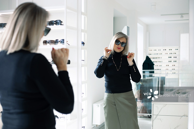 时尚中年妇女试戴新款太阳镜图片素材