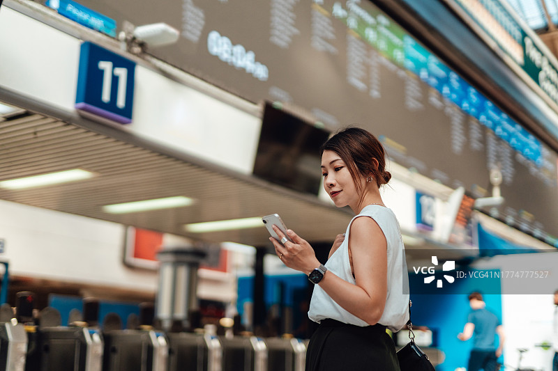 年轻的亚洲女商人在火车站查看到站离站显示屏图片素材