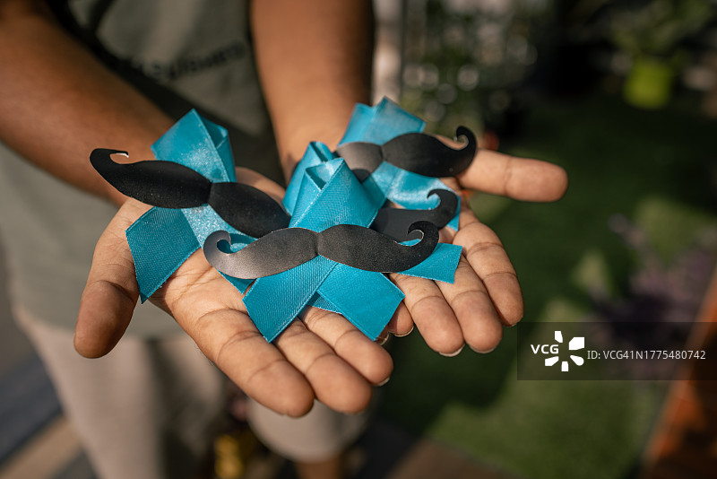 Movember蓝色十一月：手持蓝色丝带的男人图片素材