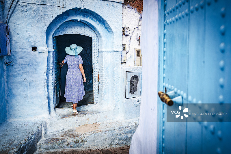 在古老麦地那打开蓝色门的女人图片素材