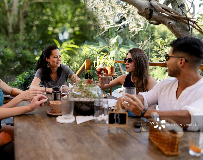 朋友们坐在户外咖啡馆一起喝咖啡图片素材