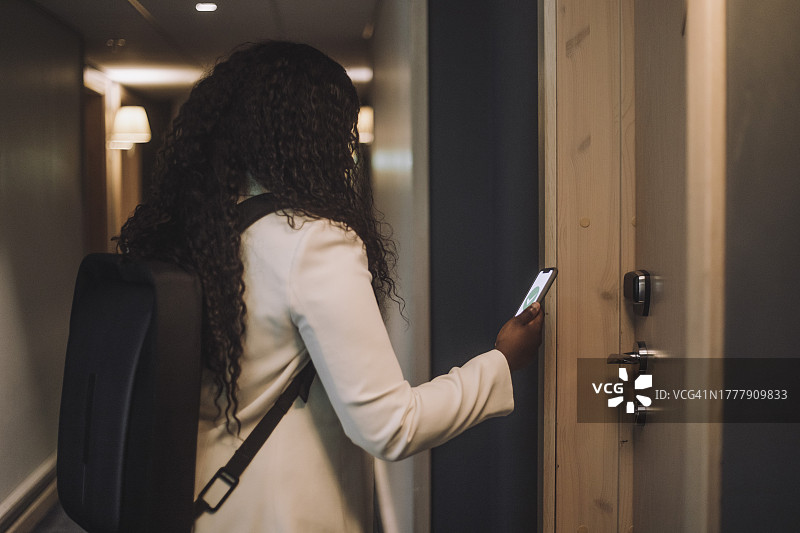使用智能手机应用进入酒店房间的女商人图片素材
