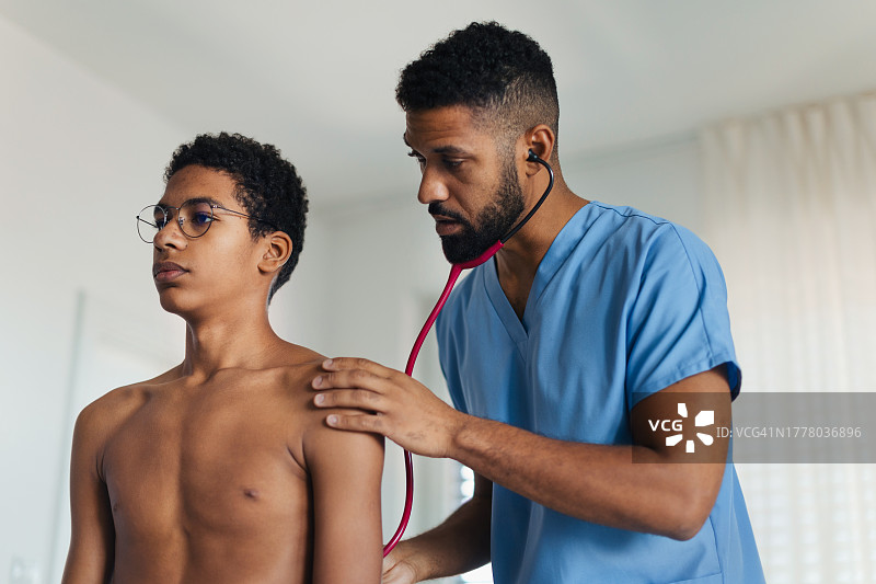 医生用听诊器检查男孩的心跳和呼吸，青少年定期体检图片素材