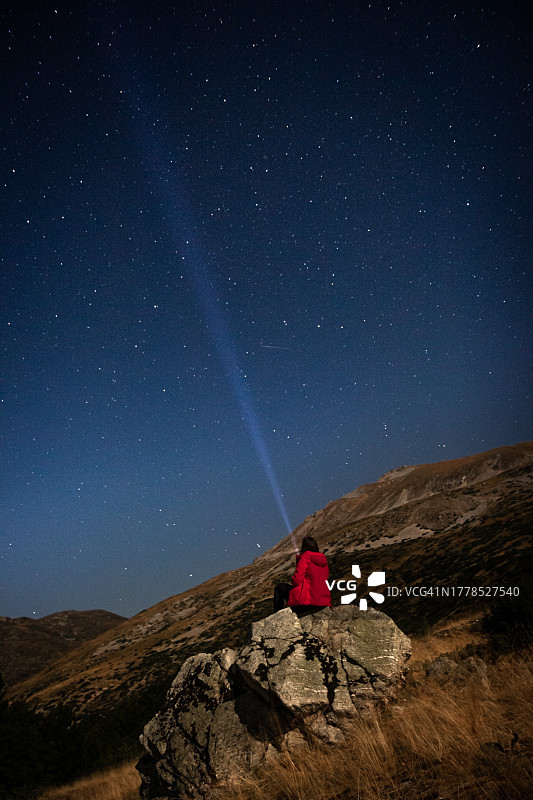 男人坐在岩石上，背景是夜晚的星空图片素材