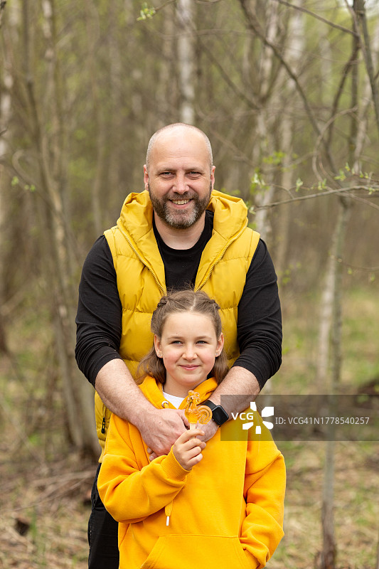 微笑的父亲抱着女儿在森林里的合影图片素材