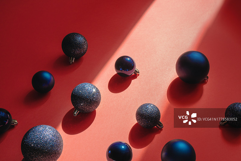 具有复制空间的抽象节日圣诞背景。阳光下红色背景上闪闪发光的迪斯科球形银色圣诞饰品。顶视图，具有对比阴影的平面构图，框架构图图片素材