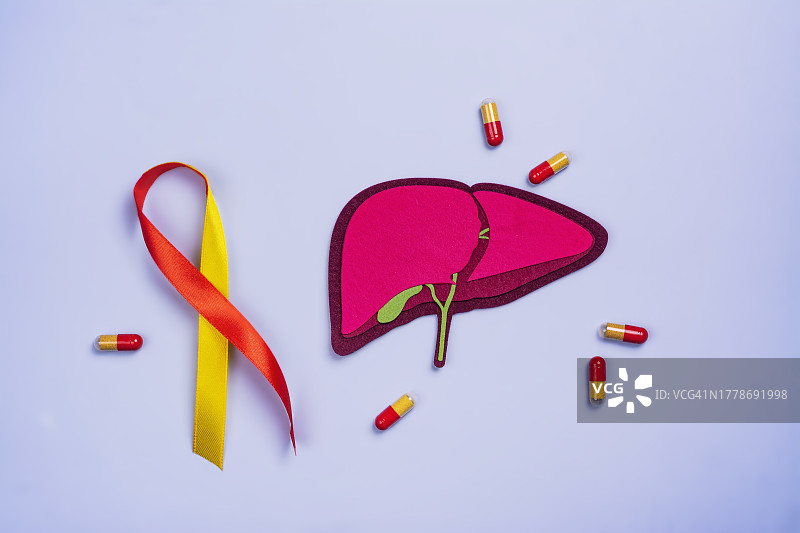 紫色桌子上的肝脏图像和胶囊特写，肝炎宣传月图片素材