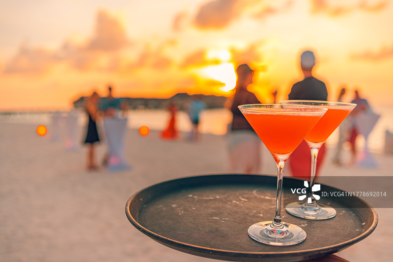 海滩日落时分，派对用鸡尾酒在托盘中特写图片素材