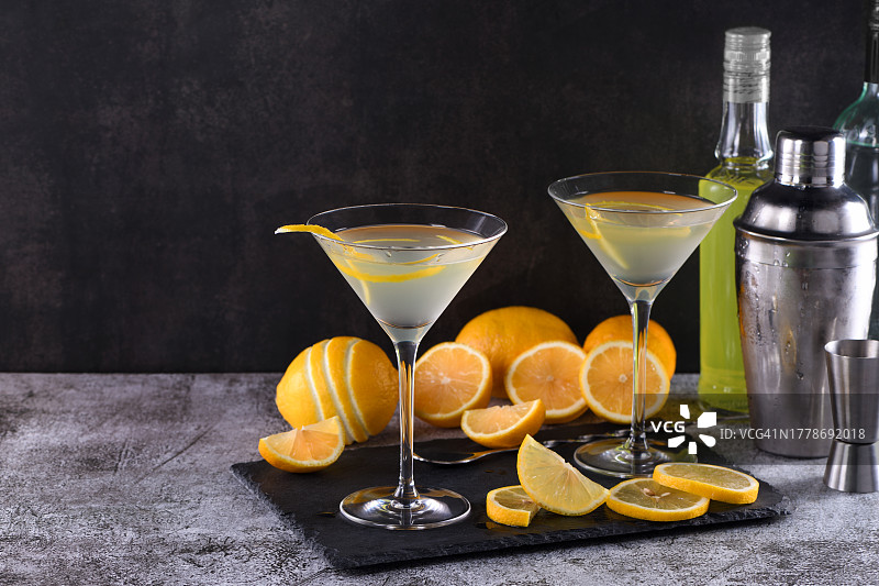 黑色背景下桌子上放着柠檬片的柠檬马提尼酒特写图片素材