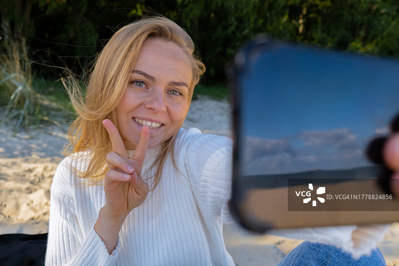 在海滩上快乐的年轻女子自拍的肖像图片素材