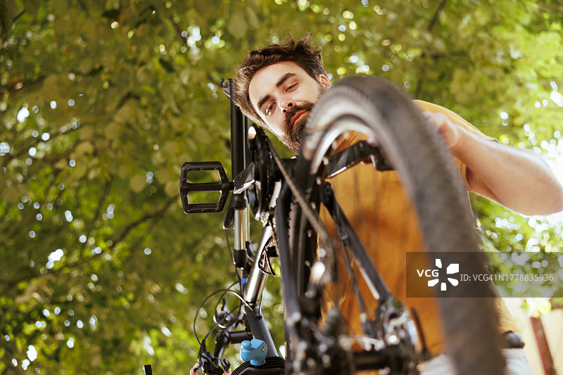 仰视户外修理自行车的男人图片素材