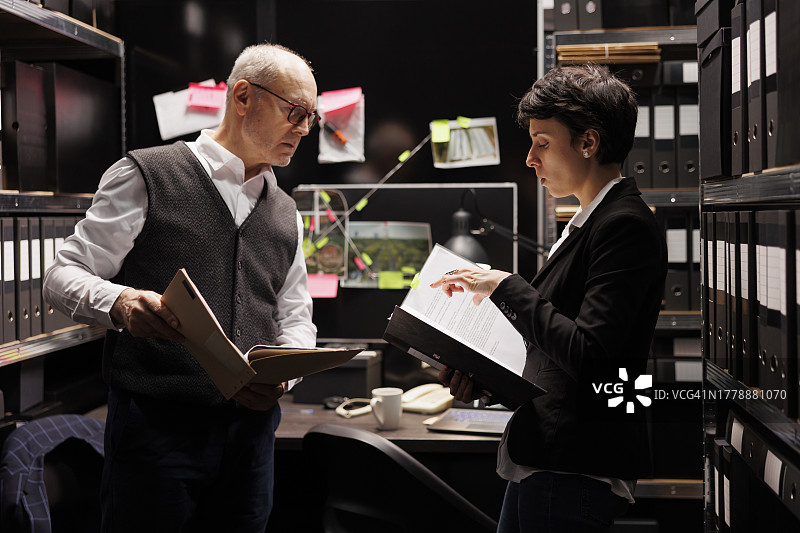 警官在档案室与女助理分析政府文件图片素材