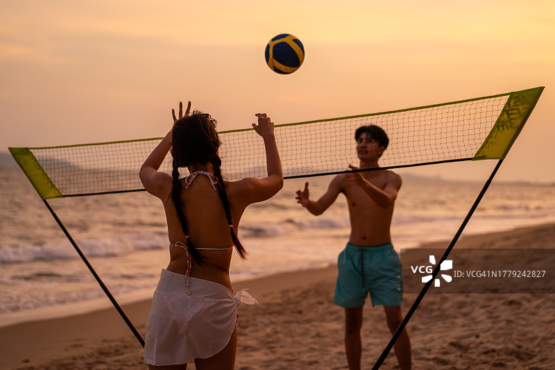 在海滩上打沙滩排球的亚洲青年男女情侣图片素材