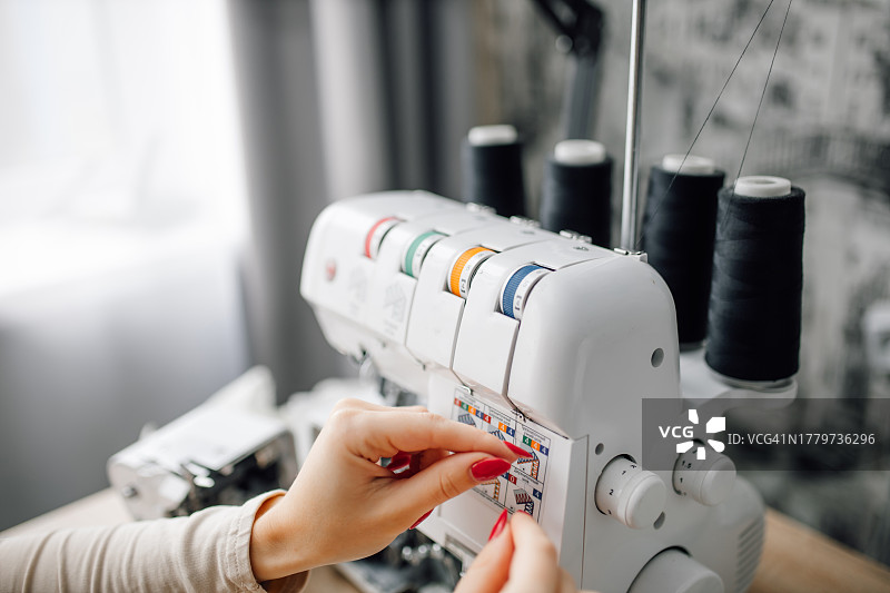 熟练的手在光线充足的缝纫车间精心准备锁边机图片素材