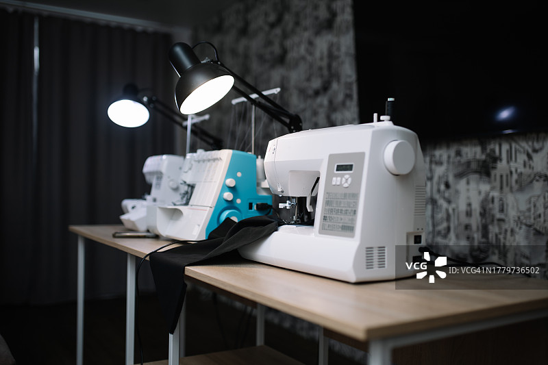 配备三台缝纫机的设备齐全的工作室中的桌子照片图片素材