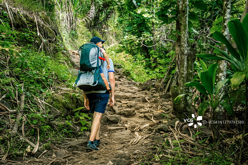 在雨林中背着孩子的年轻男人图片素材