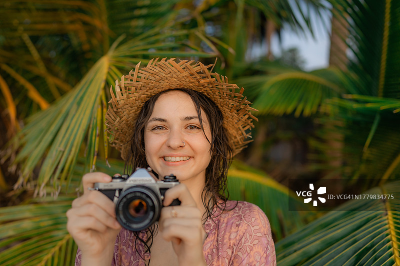 女人在海滩度假时用老式相机记录美好回忆图片素材