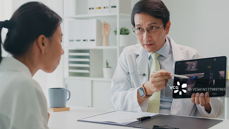 亚洲男医生向女病人展示平板电脑上的肺部X光检查结果，讲解医疗保健图片素材