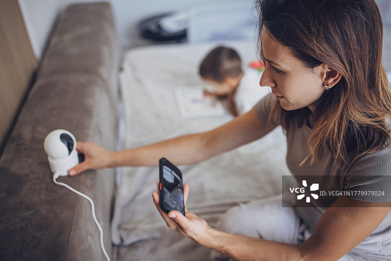 女人在家中使用智能手机控制安全摄像头图片素材