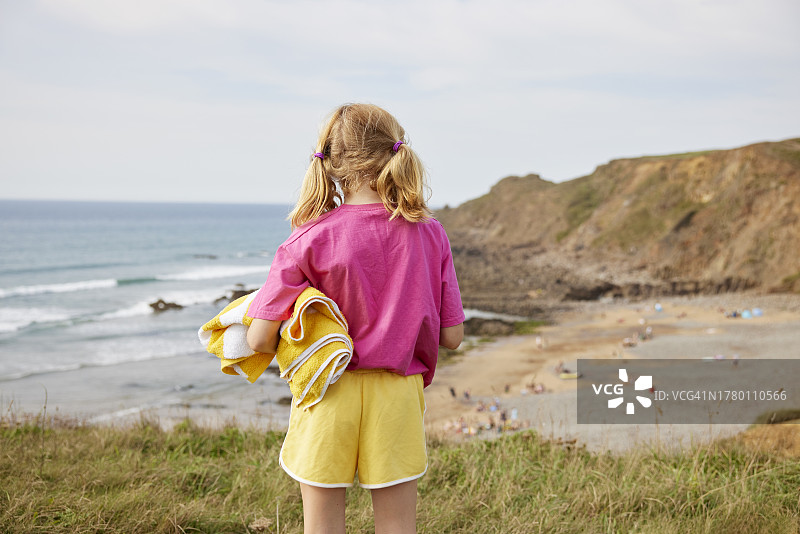 女孩站在悬崖小路上眺望海滩和大海图片素材