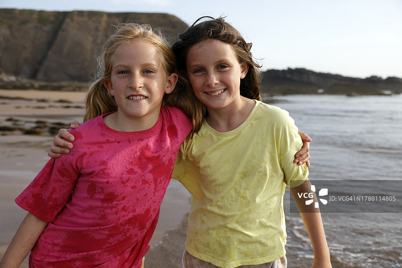 两个快乐的女孩在海滩上一起玩耍的肖像图片素材