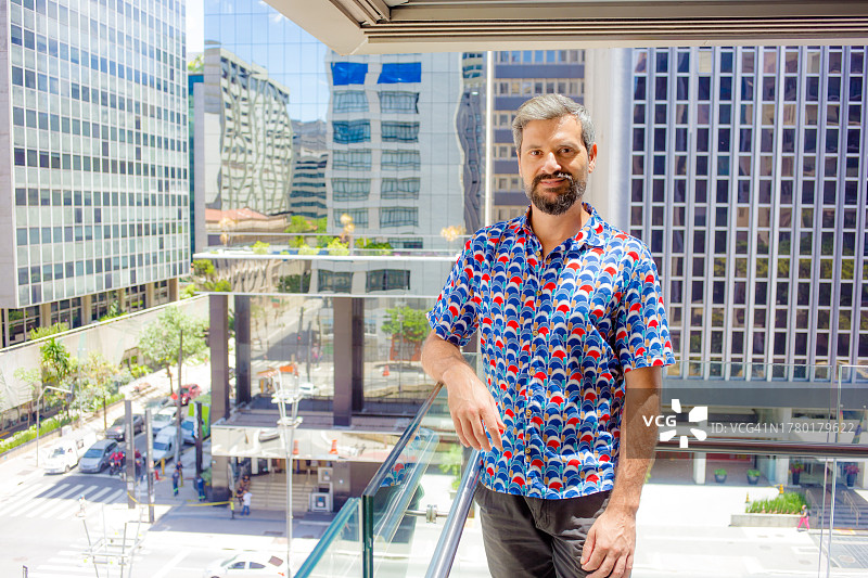 男人在建筑物阳台上看着镜头微笑图片素材