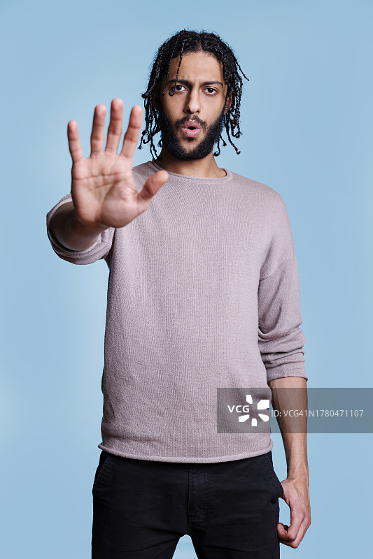 在蓝色背景下手势的年轻男人 портрет图片素材