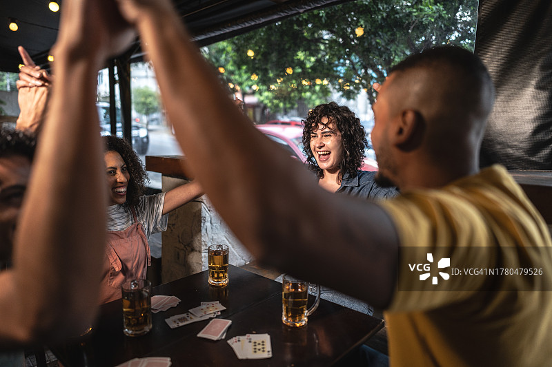 朋友们在酒吧玩纸牌庆祝图片素材