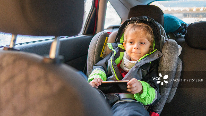 男孩在汽车安全座椅上使用手机图片素材