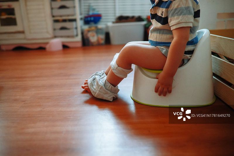 居家如厕训练：幼儿在客厅的便盆椅上（留白）图片素材