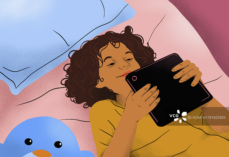 快乐女孩在家躺在床上使用平板电脑的俯视图图片素材