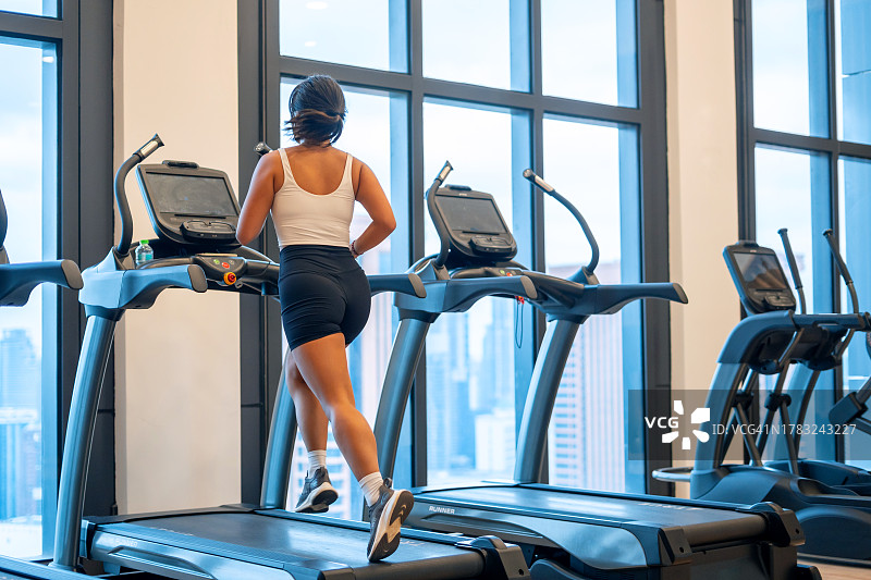 在健身房跑步机上跑步的运动型女性图片素材