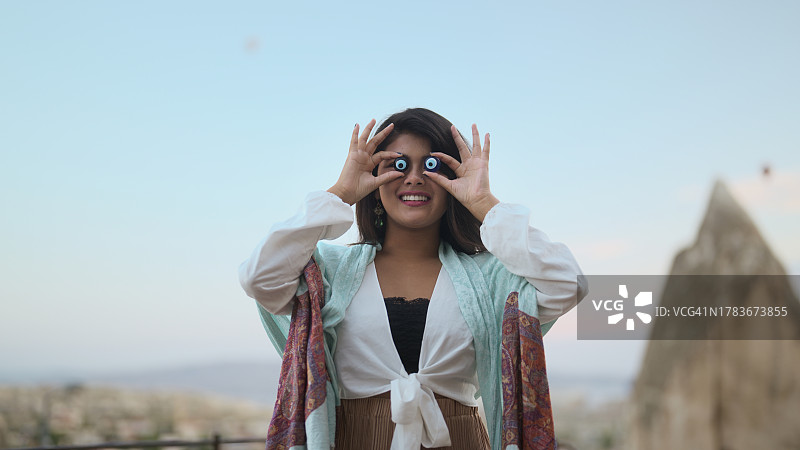 女游客用邪恶之眼玻璃珠做鬼脸的肖像图片素材