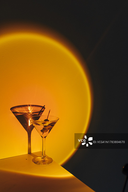 酒吧夜晚霓虹橙光下的马提尼鸡尾酒图片素材