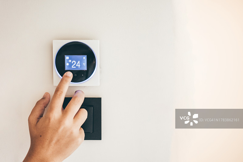 女人在家中智能温控器上调节温度图片素材