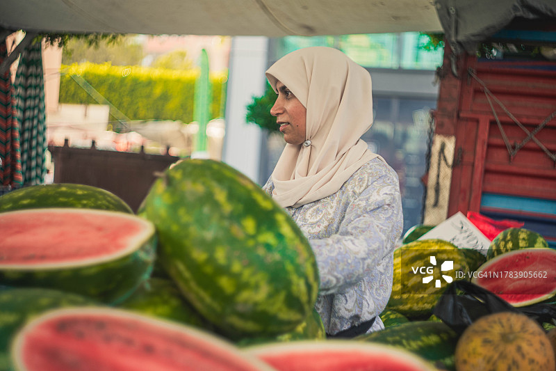 戴着头巾的穆斯林女性卖西瓜图片素材