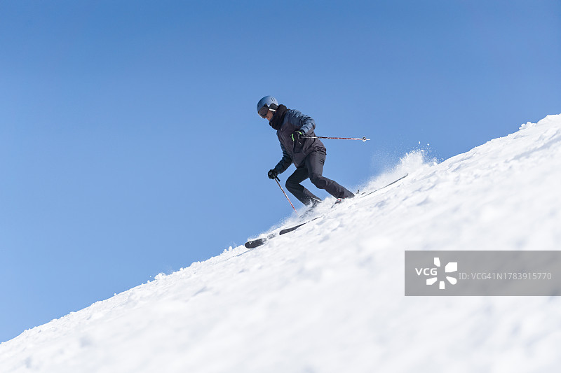 滑雪者在冬日晴天下坡图片素材