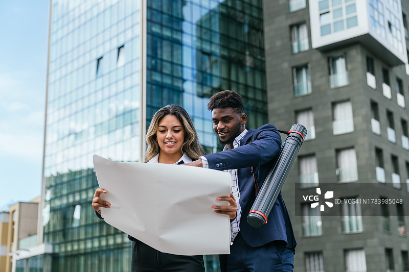 建筑师在现代办公楼外审查蓝图图片素材