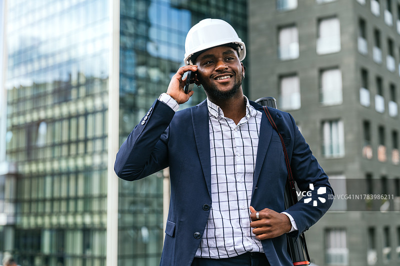 笑容满面的非洲工程师在建筑工地使用手机图片素材