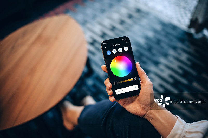 年轻亚裔女性使用智能手机设置智能家居系统图片素材