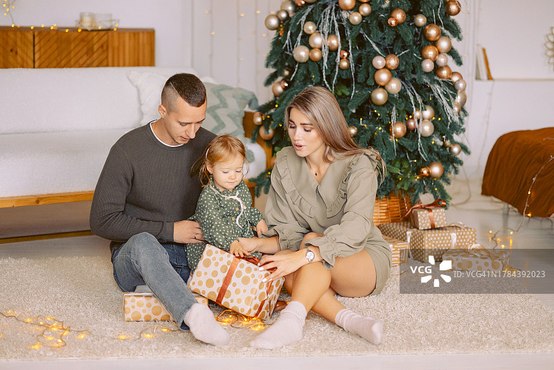 圣诞树下一家三口打开礼物图片素材