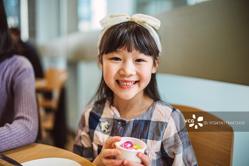 在餐厅里拿着一杯巧克力复活节彩蛋，对着镜头快乐微笑图片素材