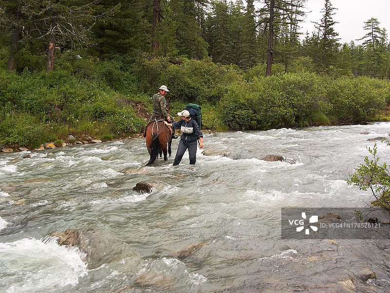 骑马的男人和女人过山间河流图片素材