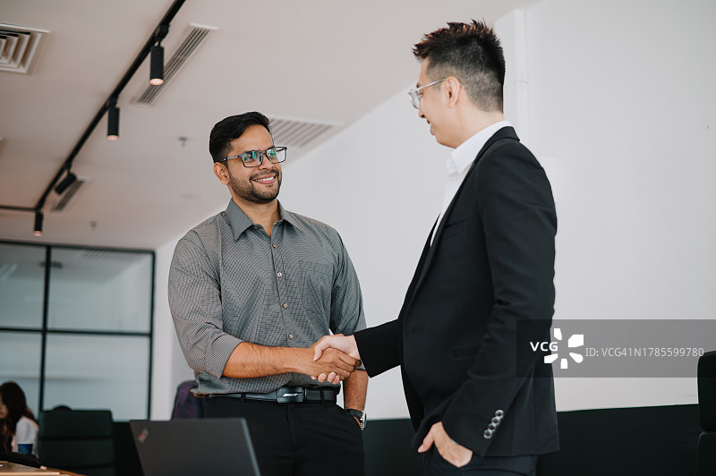 办公室里握手的华人和印度商人图片素材