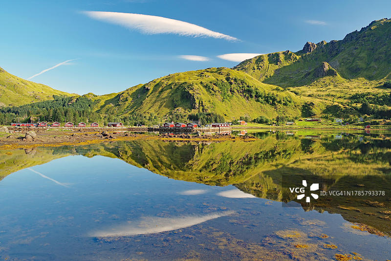 挪威诺德兰郡罗弗敦群岛布鲁斯特兰峡湾的平静水面倒影：云朵、山脉与红色木屋图片素材