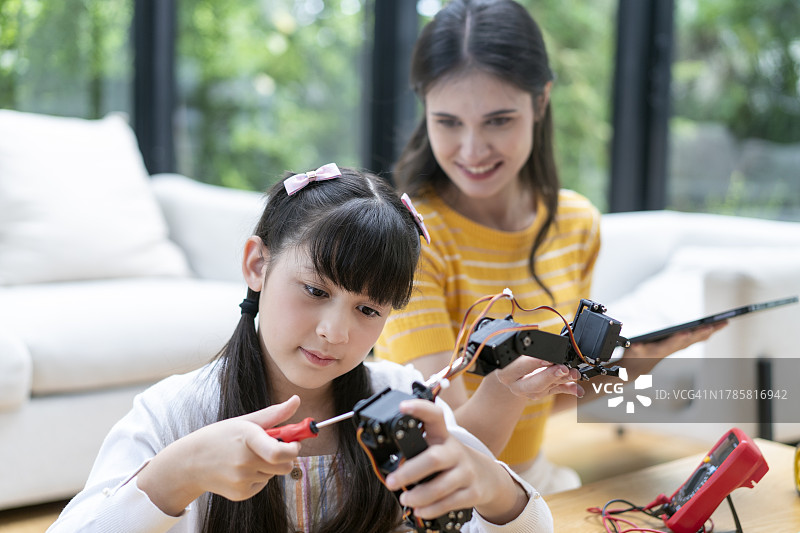 专注的女学生用螺丝刀修理她的自动驾驶机器人汽车原型图片素材