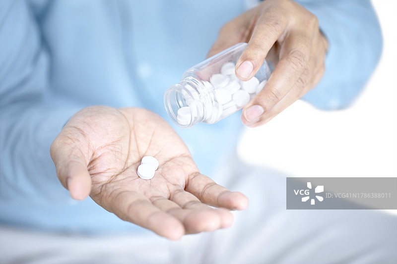 男人将药丸倒入手心图片素材